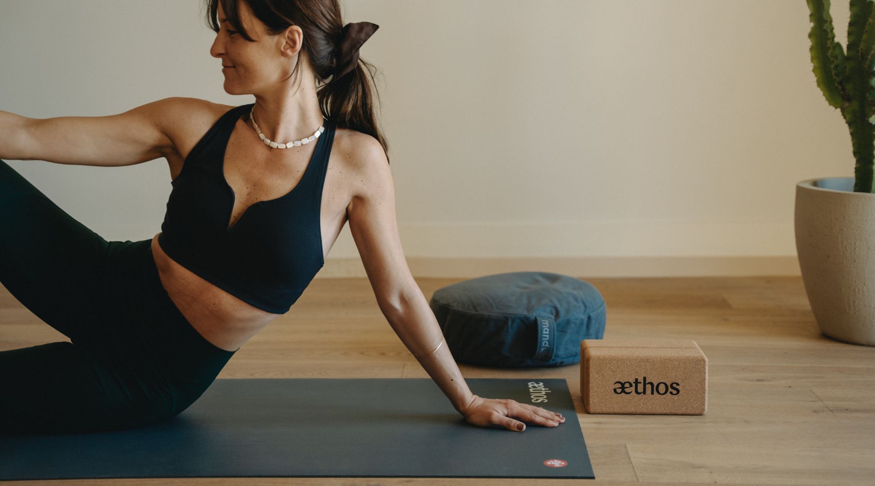 Yoga teacher practicing on the Manduka PROlite yoga mat with the lean cork block and meditation cushion.
