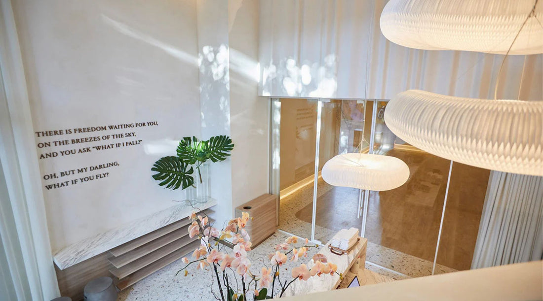 A serene interior featuring a white wall with inspirational quotes, tropical plants, soft lighting, and elegant decor.